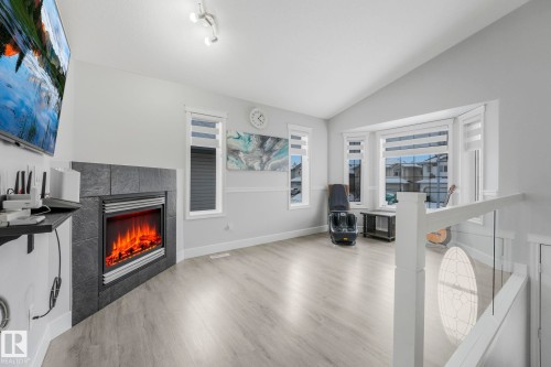 Living area featuring a tiled fireplace, vaulted ceiling, and wood finished floors - 2919 151A Avenue, Edmonton, AB - Indoor With Fireplace