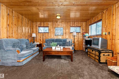 Carpeted living room featuring wooden walls, wooden ceiling, and a fireplace - 516 5 Street, Rural Lac Ste. Anne County, AB - Indoor Photo Showing Living Room