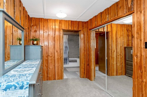 Bedroom featuring light colored carpet, wooden walls, and a closet - 516 5 Street, Rural Lac Ste. Anne County, AB - Indoor Photo Showing Bedroom