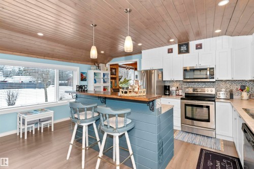 Kitchen featuring stainless steel appliances, white cabinets, a vaulted wooden ceiling, decorative light fixtures, and decorative backsplash - 516 5 Street, Rural Lac Ste. Anne County, AB - Indoor Photo Showing Kitchen