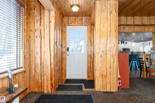 Laundry area with wood ceiling, wooden walls, stacked washer / drying machine, and light wood-type flooring - 516 5 Street, Rural Lac Ste. Anne County, AB - Indoor Photo Showing Laundry Room
