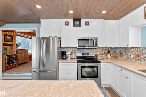 Kitchen featuring stainless steel appliances, white cabinetry, a vaulted wood ceiling, light wood-style flooring, and tasteful backsplash - 516 5 Street, Rural Lac Ste. Anne County, AB - Indoor Photo Showing Kitchen