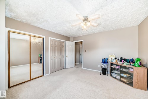 Carpeted bedroom with two closets, a ceiling fan, and a textured ceiling - 2927 30 Street, Edmonton, AB - Indoor Photo Showing Other Room