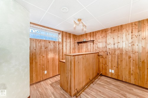 Empty room featuring light wood-type flooring, wood walls, a dry bar, and a paneled ceiling - 2927 30 Street, Edmonton, AB - Indoor Photo Showing Other Room