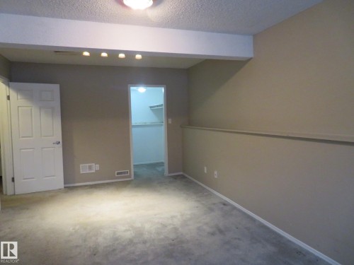 Unfurnished bedroom featuring a walk in closet, carpet, and a textured ceiling - 1855 Mill Woods Road E, Edmonton, AB - Indoor Photo Showing Other Room