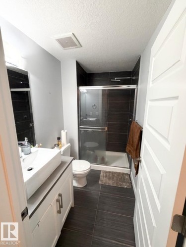 Full bathroom featuring vanity, a shower stall, and a textured ceiling - 706 5151 Windermere Bv, Edmonton, AB - Indoor Photo Showing Bathroom