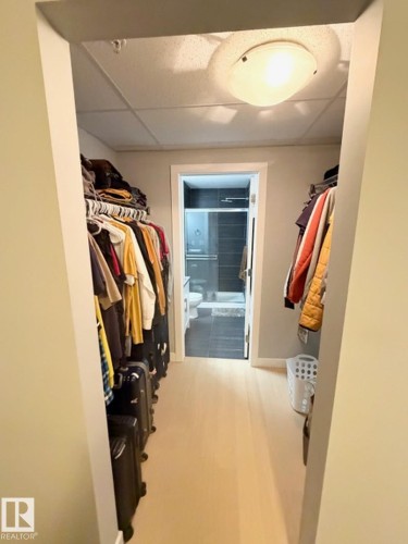 Walk in closet with a paneled ceiling and light wood-style flooring - 706 5151 Windermere Bv, Edmonton, AB - Indoor With Storage