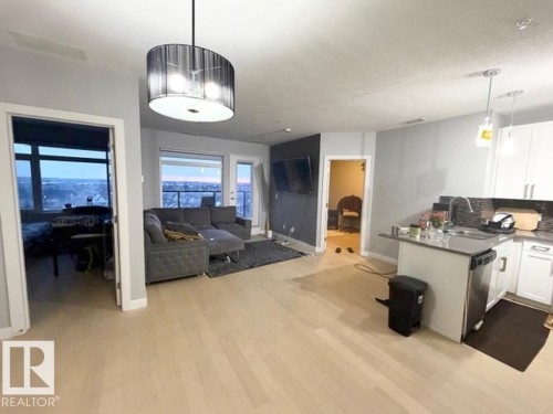 Kitchen with white cabinets, open floor plan, hanging light fixtures, decorative backsplash, and a textured ceiling - 706 5151 Windermere Bv, Edmonton, AB - Indoor