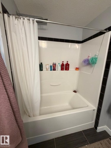 Bathroom with a textured ceiling and shower / bath combo - 706 5151 Windermere Bv, Edmonton, AB - Indoor Photo Showing Bathroom