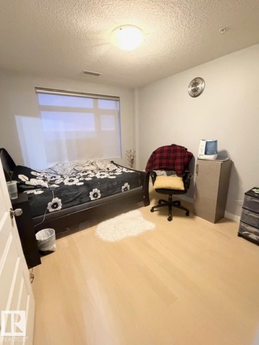 Bedroom featuring light wood-type flooring and a textured ceiling - 706 5151 Windermere Bv, Edmonton, AB - Indoor Photo Showing Other Room
