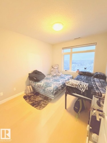 Bedroom featuring wood finished floors and a textured ceiling - 706 5151 Windermere Bv, Edmonton, AB - Indoor Photo Showing Bedroom