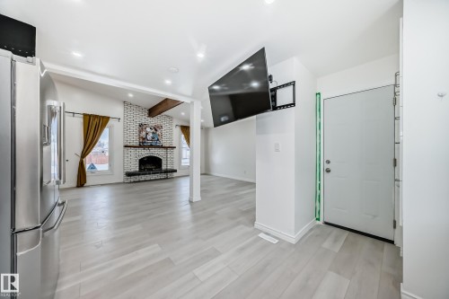 Foyer entrance featuring lofted ceiling with beams, a fireplace, light wood-style flooring, and recessed lighting - 10519 173 Avenue, Edmonton, AB - Indoor Photo Showing Other Room