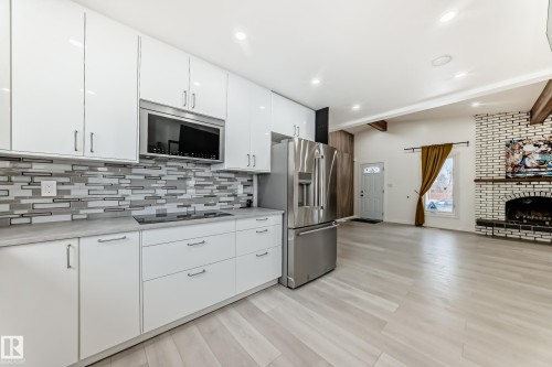 Kitchen with white cabinets, light countertops, beamed ceiling, stainless steel appliances, and light wood-style floors - 10519 173 Avenue, Edmonton, AB - Indoor Photo Showing Kitchen With Upgraded Kitchen