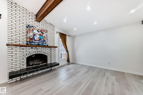 Unfurnished living room with vaulted ceiling with beams, a fireplace, and light wood-style floors - 10519 173 Avenue, Edmonton, AB - Indoor With Fireplace