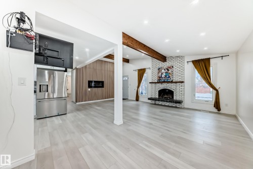 Unfurnished living room featuring a brick fireplace, light wood-style flooring, recessed lighting, and lofted ceiling with beams - 10519 173 Avenue, Edmonton, AB - Indoor With Fireplace
