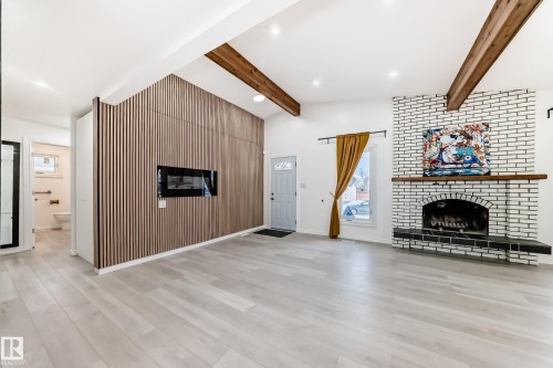 Unfurnished living room with a brick fireplace, beamed ceiling, recessed lighting, and light wood-type flooring - 10519 173 Avenue, Edmonton, AB - Indoor Photo Showing Other Room With Fireplace