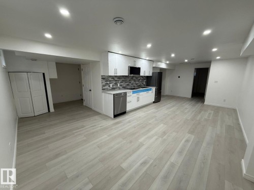Kitchen featuring white cabinetry, open floor plan, light countertops, stainless steel appliances, and light wood-type flooring - 10519 173 Avenue, Edmonton, AB - Indoor