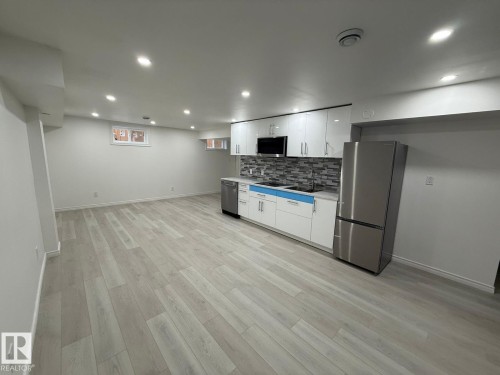 Kitchen with white cabinetry, stainless steel appliances, recessed lighting, tasteful backsplash, and light wood-style flooring - 10519 173 Avenue, Edmonton, AB - Indoor