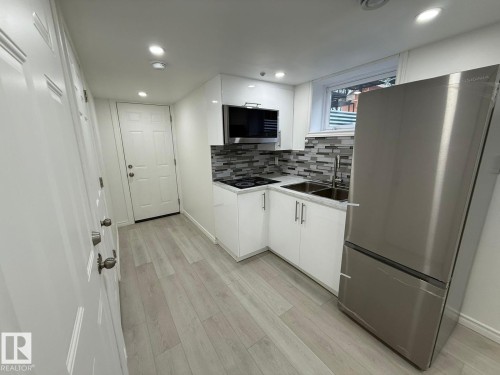 Kitchen featuring stainless steel appliances, white cabinets, light countertops, light wood-style flooring, and recessed lighting - 10519 173 Avenue, Edmonton, AB - Indoor Photo Showing Kitchen With Double Sink