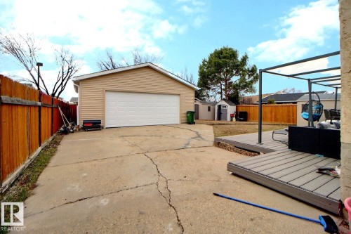 Detached garage with horizontal siding and a white garage door, featuring a concrete driveway and an expansive backyard with a composite deck - 10519 173 Avenue, Edmonton, AB - Outdoor