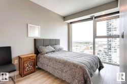 Bedroom featuring light wood-type flooring, a textured ceiling, and a view of city - 