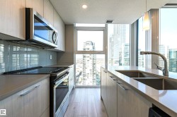 Kitchen featuring stainless steel appliances, hanging light fixtures, a textured ceiling, modern cabinets, and a wall of windows - 