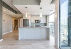 Kitchen with modern cabinets, stainless steel appliances, decorative light fixtures, backsplash, and light stone countertops - 