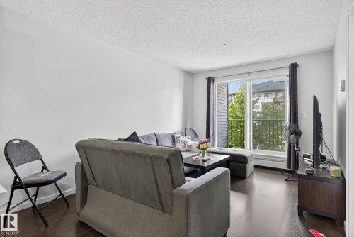 Living area featuring a textured ceiling and wood finished floors - 209 3353 16A, Edmonton, AB - Indoor Photo Showing Living Room