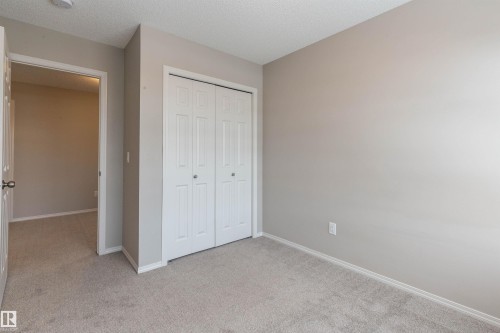 Unfurnished bedroom featuring light carpet, a closet, and a textured ceiling - 17259 9A Avenue Sw, Edmonton, AB - Indoor