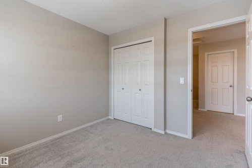 Unfurnished bedroom with light carpet, a closet, and a textured ceiling - 17259 9A Avenue Sw, Edmonton, AB - Indoor