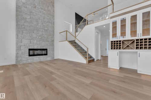 Unfurnished living room with a high ceiling, a fireplace, and light wood finished floors - 159 Graybriar Dr, Stony Plain, AB - Indoor Photo Showing Other Room With Fireplace