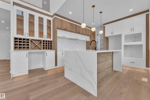 Kitchen with an island with sink, light wood-style flooring, light stone counters, modern cabinets, and two tone cabinets - 159 Graybriar Dr, Stony Plain, AB - Indoor Photo Showing Kitchen
