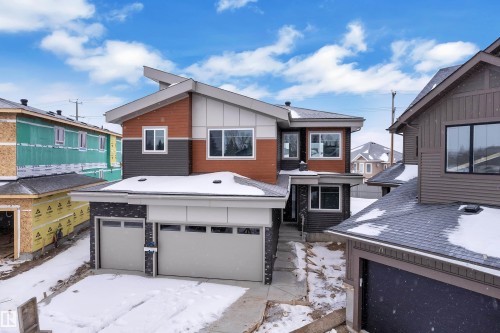 View of front of house featuring an attached garage, board and batten siding, and a residential view - 159 Graybriar Dr, Stony Plain, AB - Outdoor With Facade
