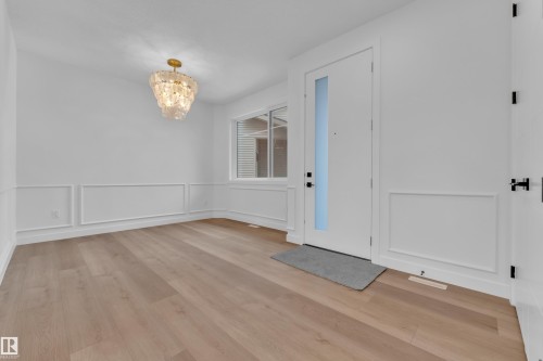 Foyer entrance with hanging lights, a decorative wall, light wood-style flooring, and wainscoting - 159 Graybriar Dr, Stony Plain, AB - Indoor Photo Showing Other Room