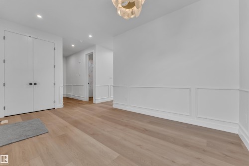 Foyer entrance featuring a decorative wall, a wainscoted wall, light wood-style flooring, and hanging lights - 159 Graybriar Dr, Stony Plain, AB - Indoor Photo Showing Other Room