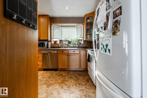 Kitchen with stainless steel appliances, wood finish cabinets, dark countertops, glass fronted cabinets, and recessed lighting - 69 Amherst Crescent, St. Albert, AB - Indoor Photo Showing Kitchen
