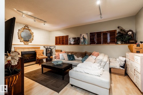 Living area with rail lighting, a fireplace, light wood-type flooring, and a textured ceiling - 69 Amherst Crescent, St. Albert, AB - Indoor Photo Showing Living Room With Fireplace