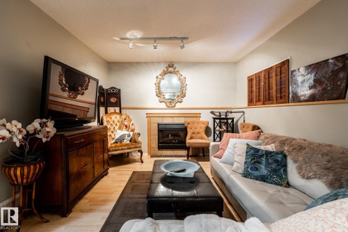 Living area featuring a tile fireplace, rail lighting, a textured ceiling, and light wood-style flooring - 69 Amherst Crescent, St. Albert, AB - Indoor Photo Showing Living Room With Fireplace