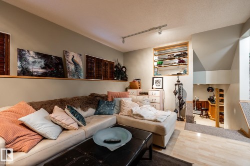 Living area with rail lighting, a textured ceiling, and light wood-type flooring - 69 Amherst Crescent, St. Albert, AB - Indoor Photo Showing Living Room