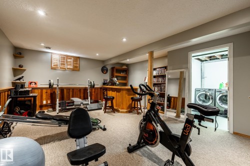 Workout room with bar area, light carpet, recessed lighting, washing machine and dryer, and a wainscoted wall - 69 Amherst Crescent, St. Albert, AB - Indoor Photo Showing Other Room