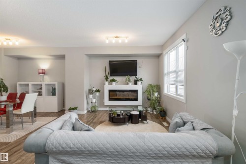 Living room featuring wood finished floors and a glass covered fireplace - 31 2803 James Mowatt Trail, Edmonton, AB - Indoor Photo Showing Bedroom With Fireplace
