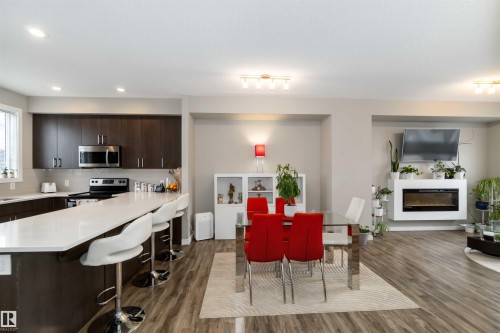Dining area with a glass covered fireplace, dark wood finished floors, and recessed lighting - 31 2803 James Mowatt Trail, Edmonton, AB - Indoor