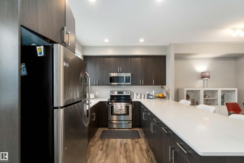 Kitchen with stainless steel appliances, modern cabinets, a breakfast bar, a peninsula, and recessed lighting - 31 2803 James Mowatt Trail, Edmonton, AB - Indoor Photo Showing Kitchen