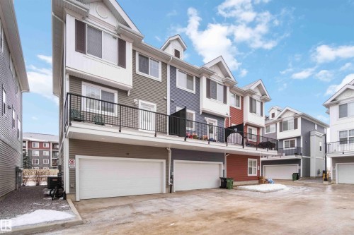 Rear view of house featuring a balcony, a residential view, a garage, and concrete driveway - 31 2803 James Mowatt Trail, Edmonton, AB - Outdoor With Balcony With Facade