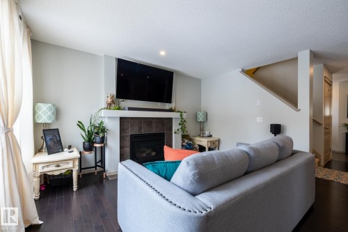 Living room featuring dark wood-style flooring, a textured ceiling, a tiled fireplace, and recessed lighting - 3312 17B Avenue, Edmonton, AB - Indoor Photo Showing Living Room With Fireplace