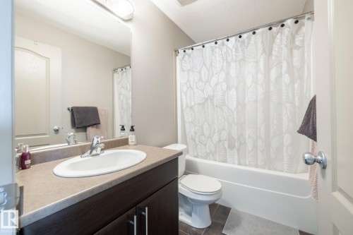 Full bath featuring vanity, shower / bathtub combination with curtain, a textured ceiling, and dark tile patterned floors - 3312 17B Avenue, Edmonton, AB - Indoor Photo Showing Bathroom