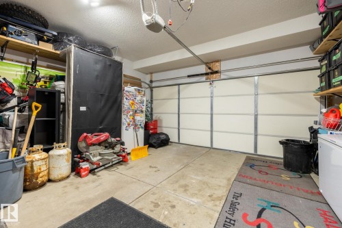 Garage featuring white refrigerator, a garage door opener, and freestanding refrigerator - 3312 17B Avenue, Edmonton, AB - Indoor Photo Showing Garage
