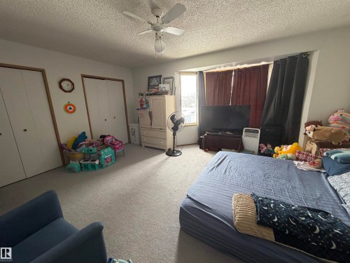 Carpeted bedroom with two closets, a textured ceiling, and a ceiling fan - 101 1 Aberdeen Way, Stony Plain, AB - Indoor Photo Showing Other Room