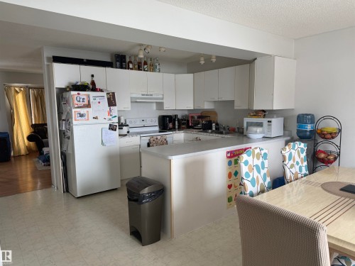 Kitchen with light flooring, white appliances, a peninsula, white cabinetry, and light countertops - 101 1 Aberdeen Way, Stony Plain, AB - Indoor Photo Showing Kitchen