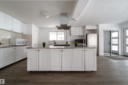 Kitchen featuring white cabinets, island exhaust hood, dark wood finished floors, and white appliances - 11430 81 Street, Edmonton, AB - Indoor Photo Showing Kitchen
